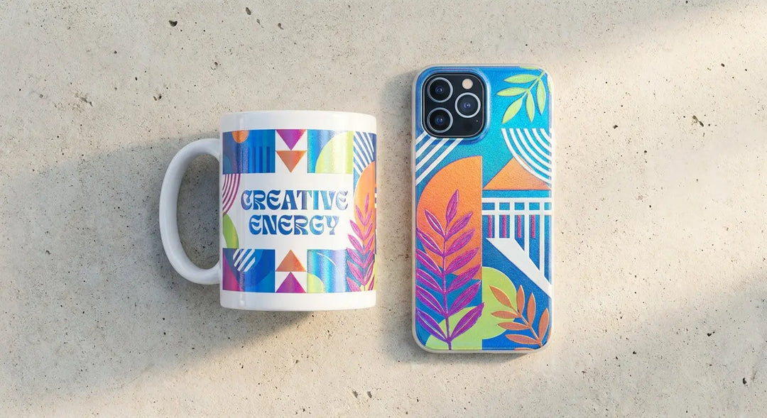 A flat lay of a white ceramic mug and a smartphone case featuring vivid custom UV DTF transfers, photographed on a light concrete surface with soft natural lighting.